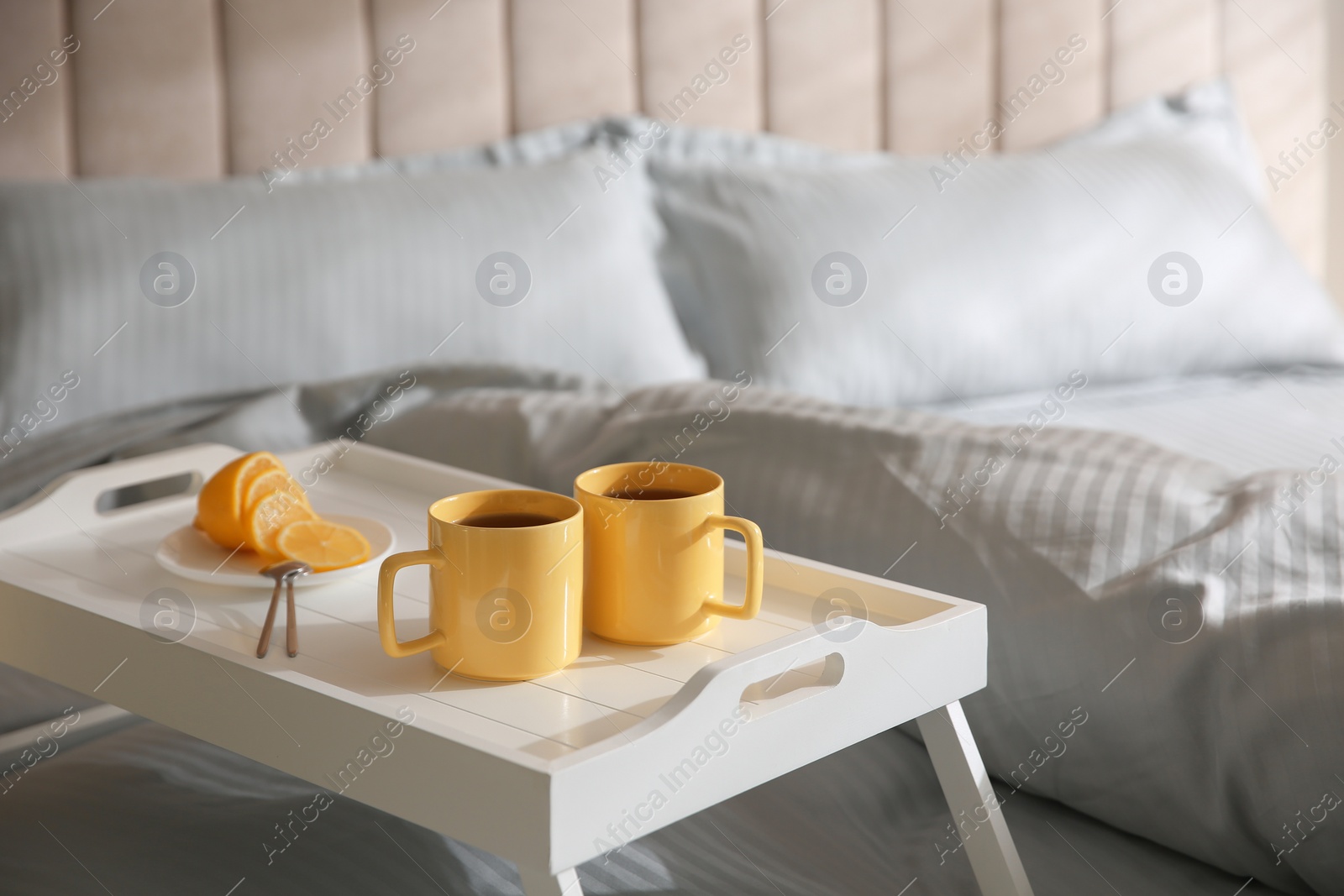 Photo of Soft blanket and tray with breakfast on bed, closeup