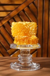 Glass stand with natural honeycombs on wooden table