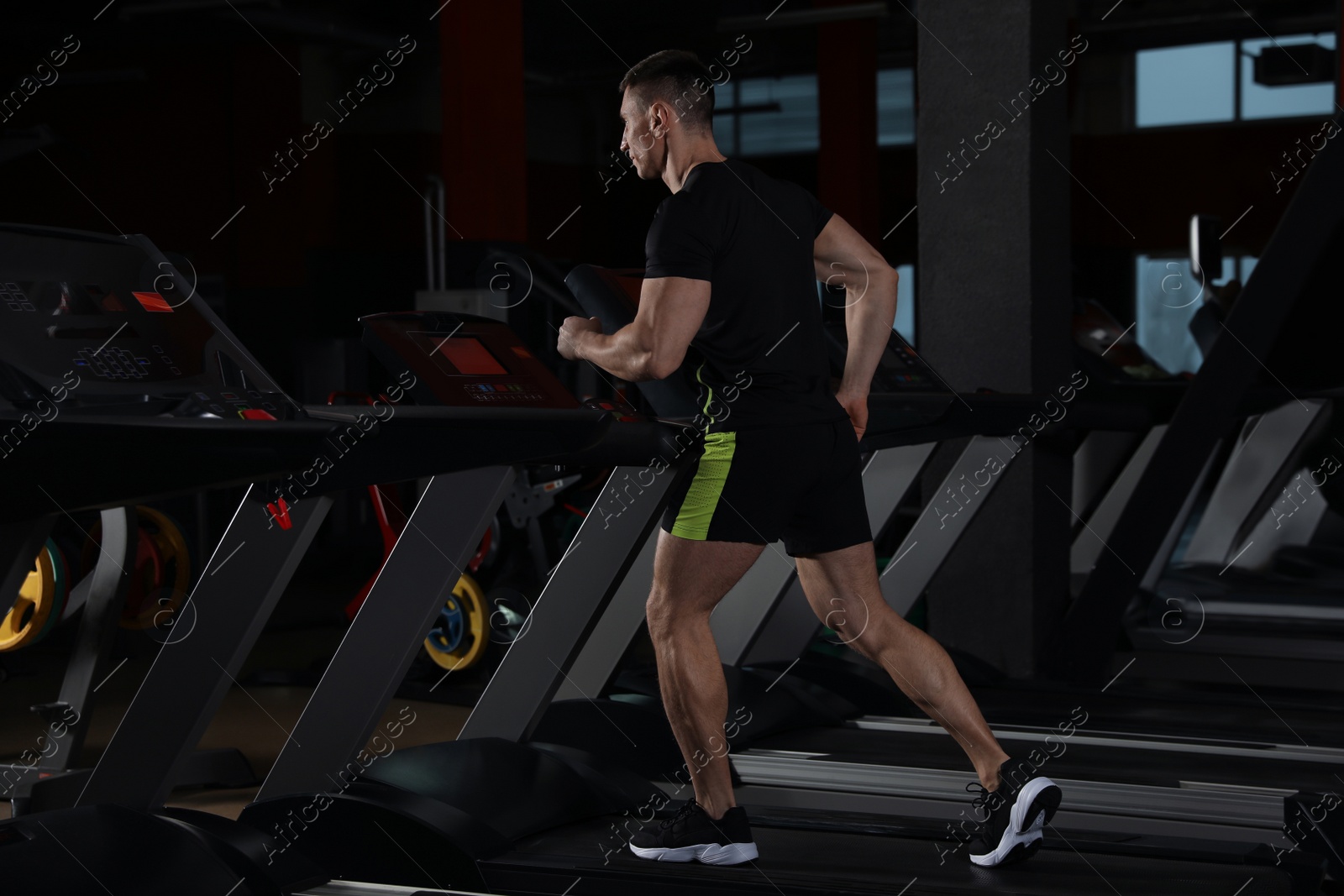 Photo of Man working out on treadmill in modern gym