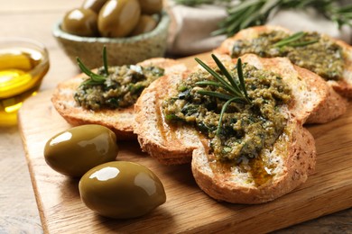 Photo of Tasty bruschettas with pesto and rosemary on wooden board, closeup