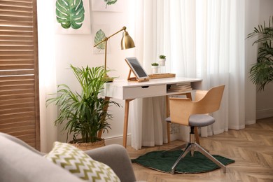 Photo of Beautiful fresh house plants near workplace in room