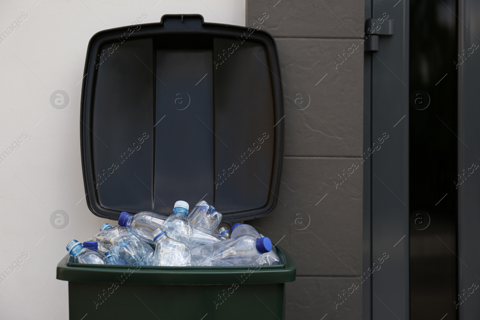 Photo of Many used plastic bottles in trash bin outdoors. Recycling problem