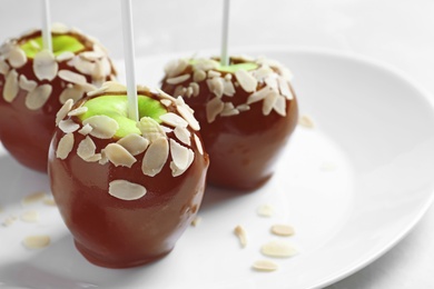 Plate with delicious caramel apples on light background