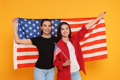 Photo of 4th of July - Independence Day of USA. Happy woman and her daughter with American flags on yellow background
