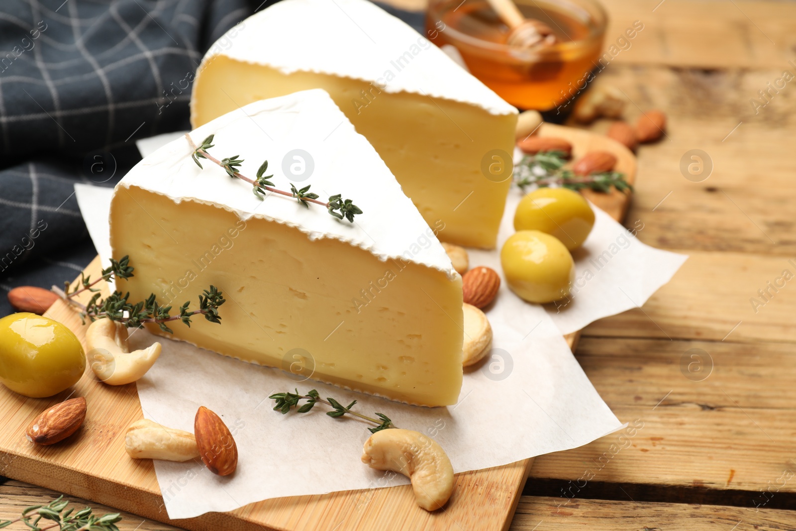 Photo of Tasty Camembert cheese with thyme, honey and nuts on wooden table