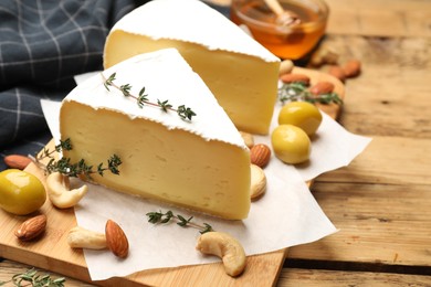 Tasty Camembert cheese with thyme, honey and nuts on wooden table