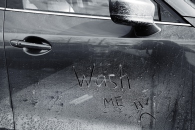 Photo of Inscription WASH ME and sad smiley on car door, closeup