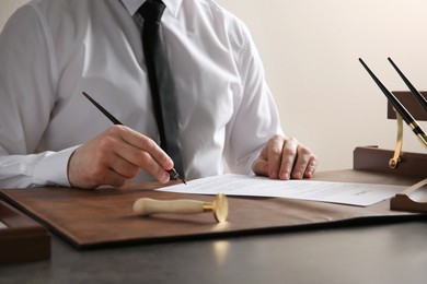 Photo of Male notary signing document at table, closeup