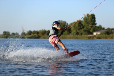 Photo of Teenage boy wakeboarding on river. Extreme water sport