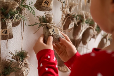 Little girl taking gift from New Year advent calendar indoors, closeup