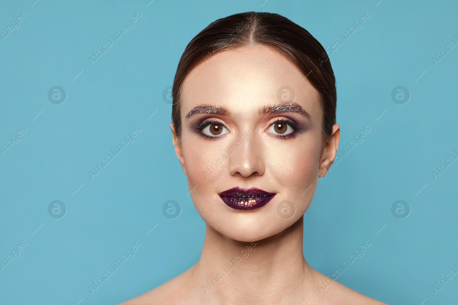 Photo of Beautiful young woman with glitter makeup on blue background