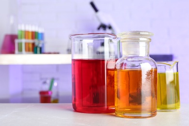 Different glassware with samples on table in chemistry laboratory. Space for text