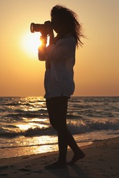 Photo of Photographer taking photo of sea with professional camera at sunset