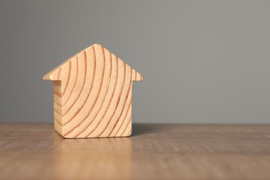 Mortgage concept. House model on wooden table against grey background, space for text