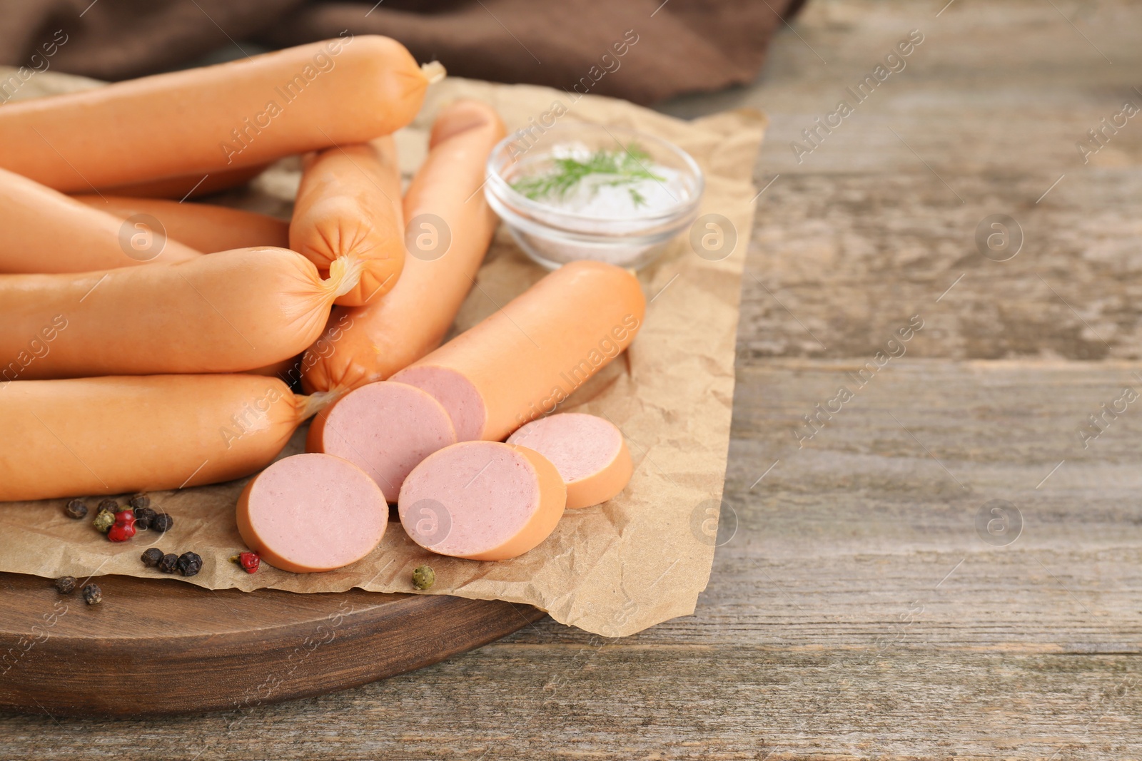 Photo of Tasty sausages and peppercorns on wooden table, closeup with space for text. Meat product