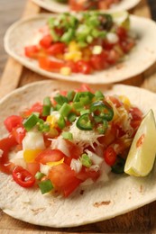 Photo of Delicious tacos with vegetables, green onion, lime and ketchup on table, closeup