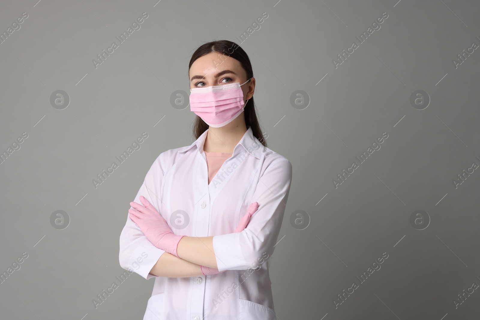 Photo of Cosmetologist in medical uniform on grey background