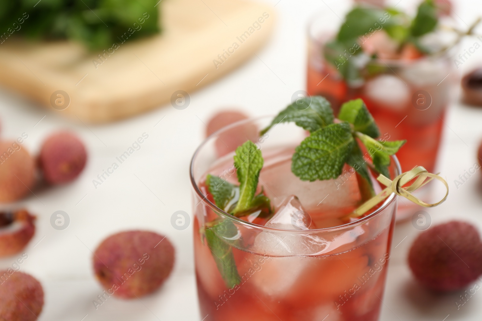 Photo of Lychee cocktail with mint and ice on white table, closeup