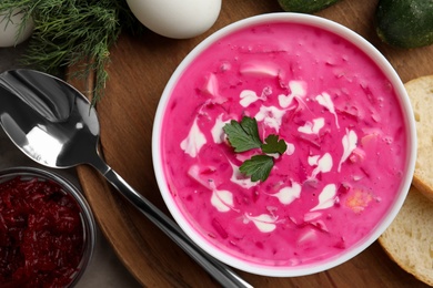 Photo of Delicious cold summer beet soup on wooden board, flat lay