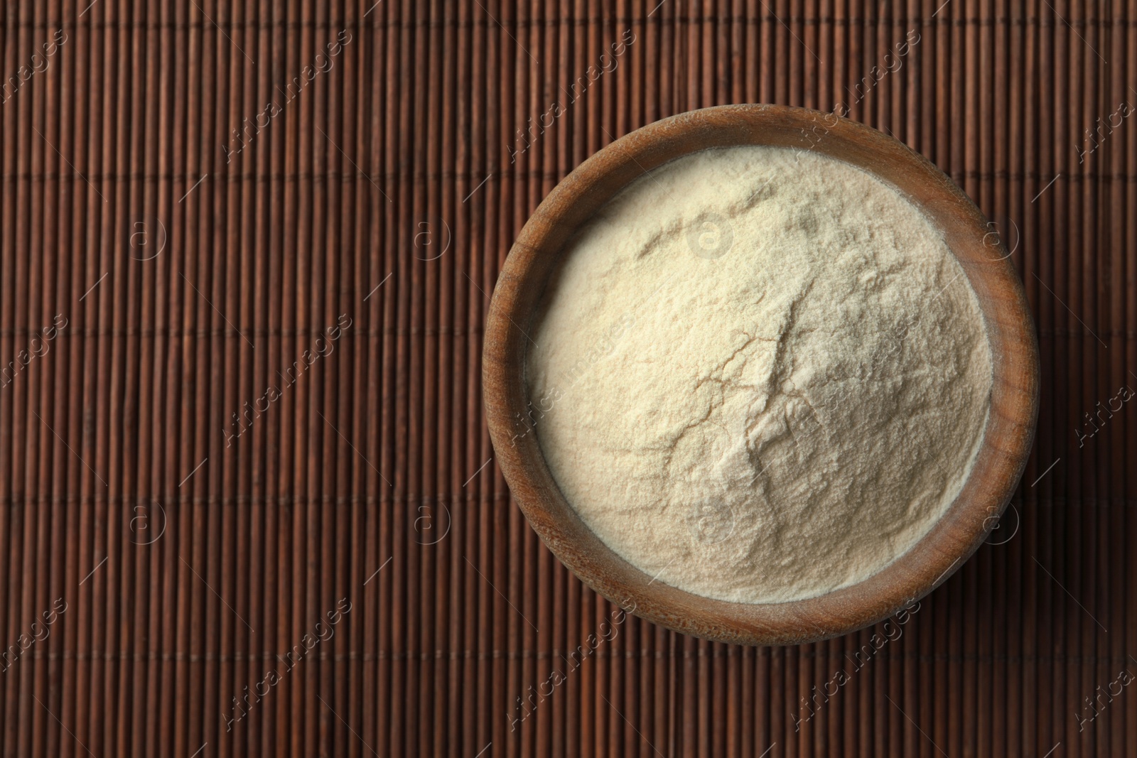 Photo of Bowl of agar-agar powder on bamboo mat, top view. Space for text