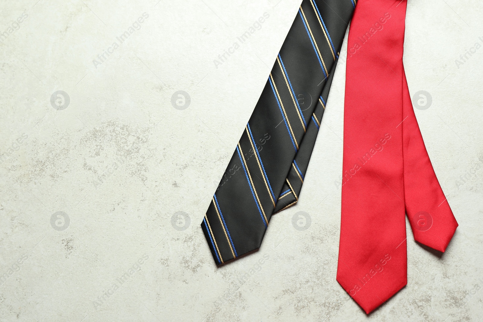 Photo of Two neckties on light textured table, top view. Space for text