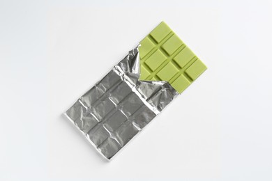 Tasty matcha chocolate bar wrapped in foil on white background, top view