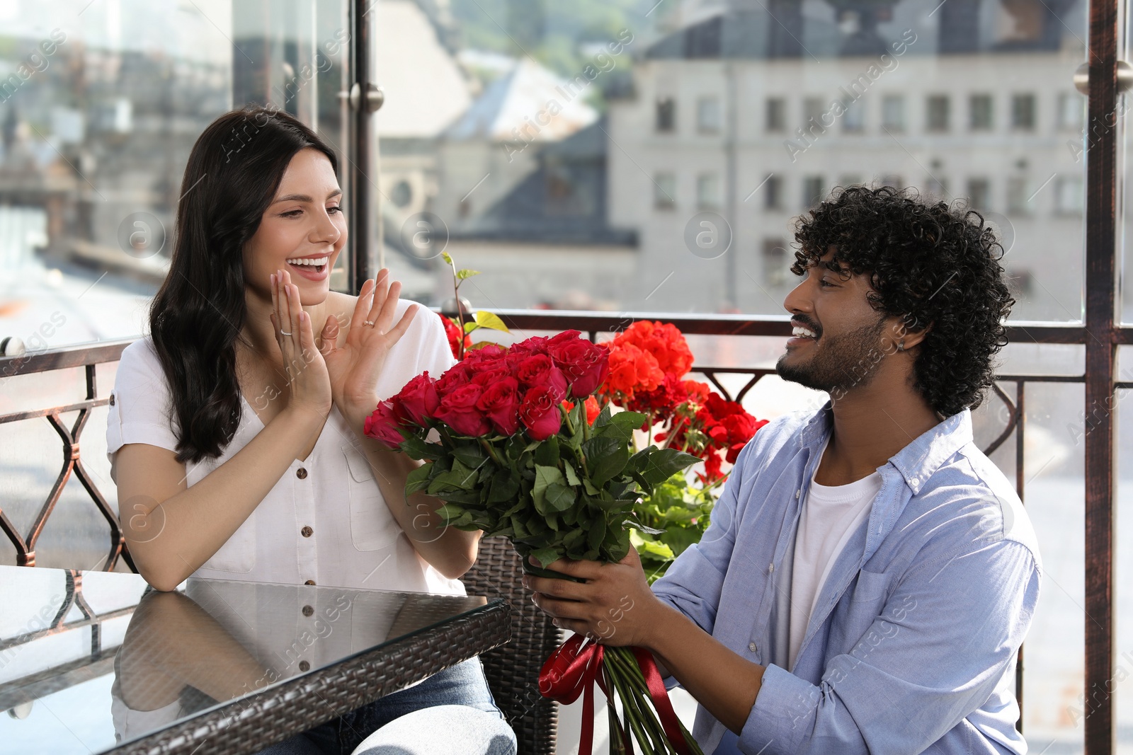 Photo of International dating. Handsome man presenting roses to his beloved woman in restaurant