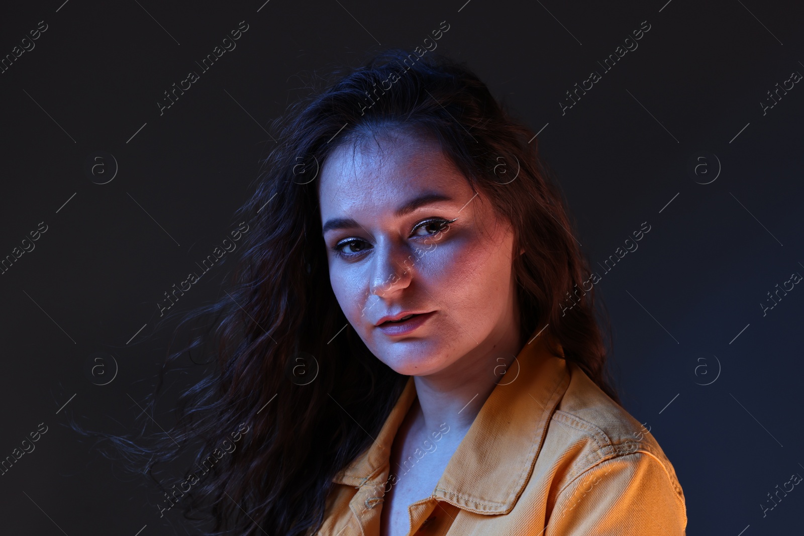 Photo of Portrait of beautiful young woman on color background with neon lights