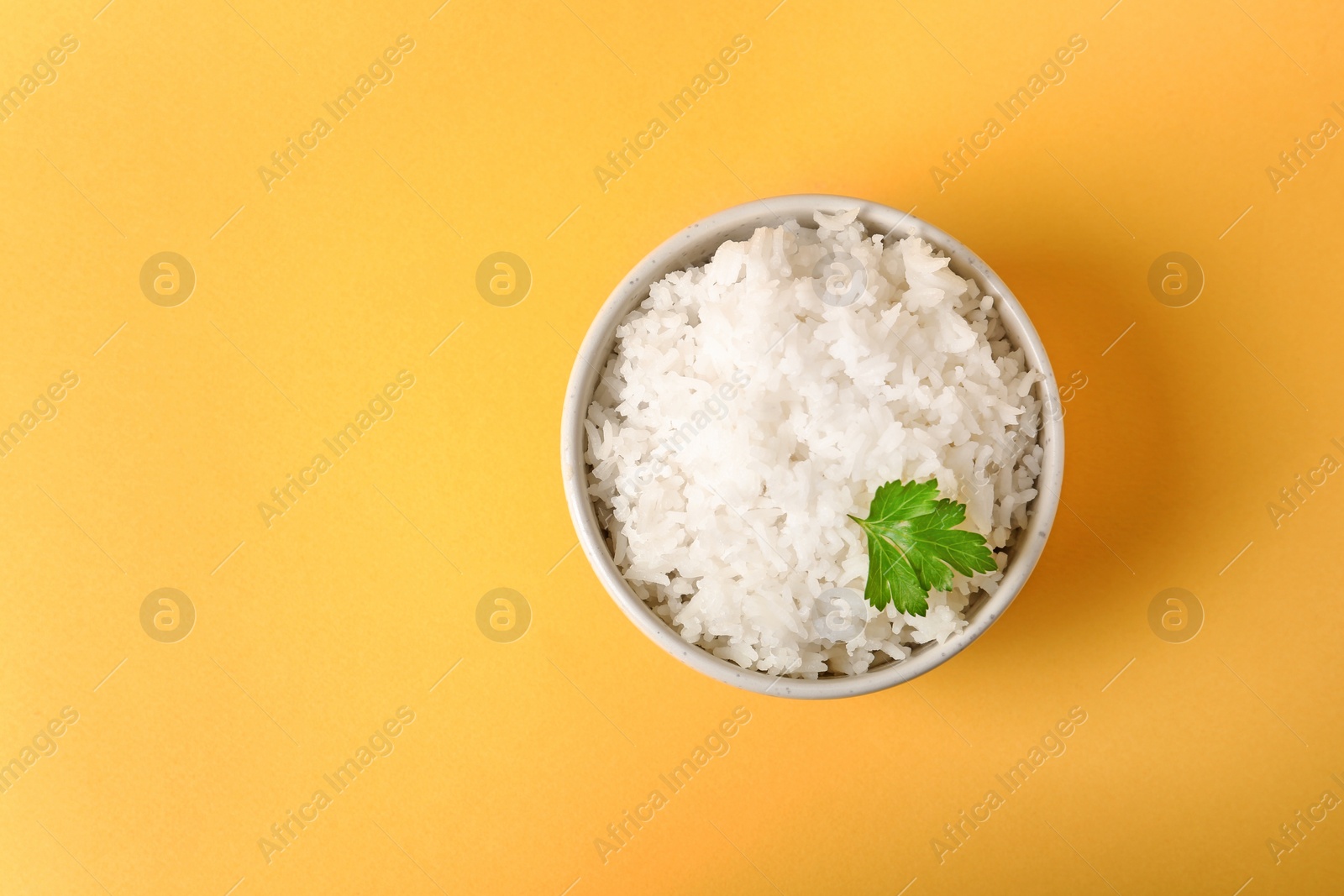 Photo of Bowl of boiled rice on color background, top view with space for text