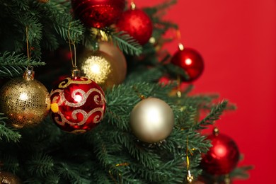 Photo of Beautifully decorated Christmas tree against red background, closeup
