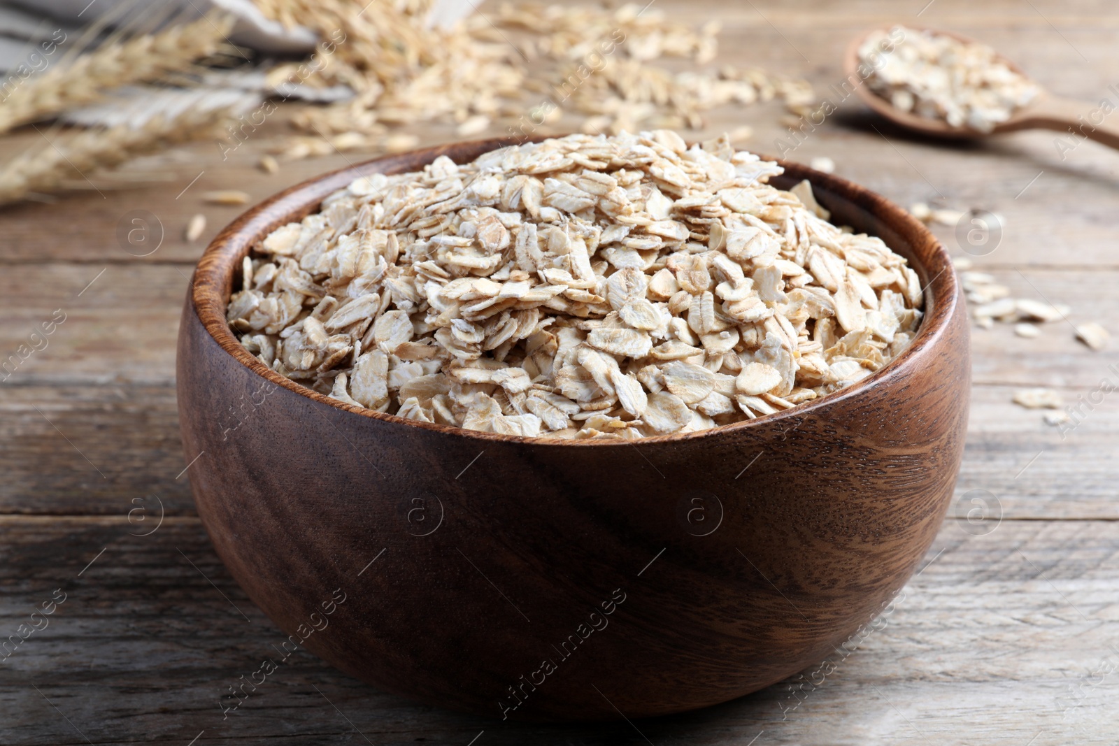 Photo of Bowl with oatmeal on wooden table, closeup