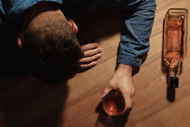 Addicted man with alcoholic drink at wooden table, top view