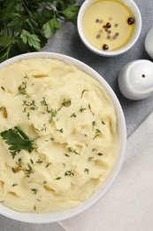 Photo of Bowl of tasty mashed potato, parsley, olive oil and pepper on grey marble table, flat lay