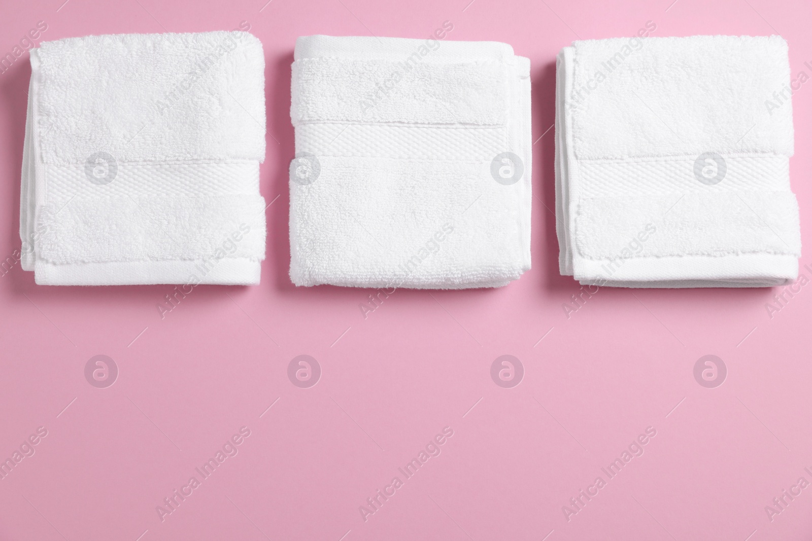 Photo of Soft folded white towels on violet background, flat lay. Space for text