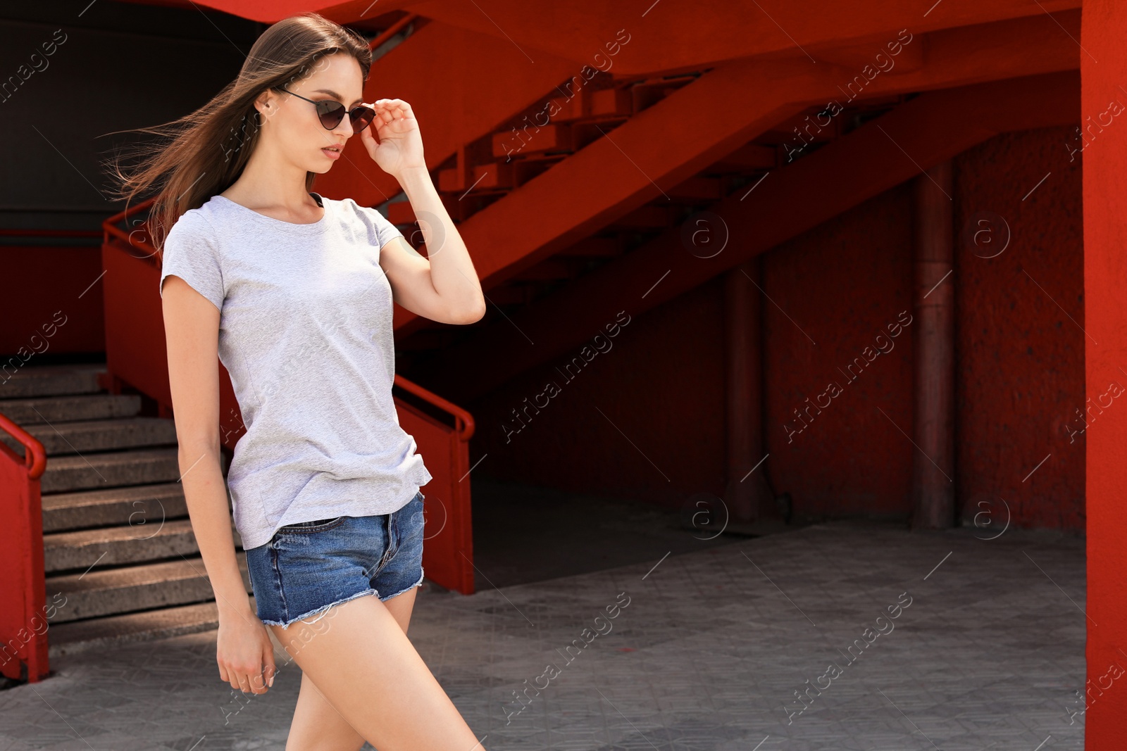 Photo of Young woman wearing gray t-shirt on street. Urban style