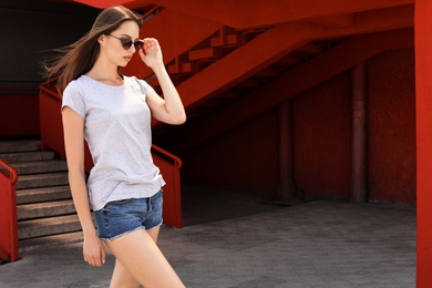 Photo of Young woman wearing gray t-shirt on street. Urban style