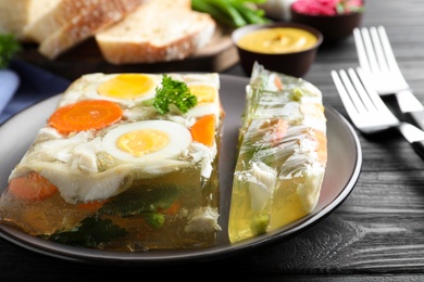 Photo of Delicious fish aspic served on black wooden table, closeup