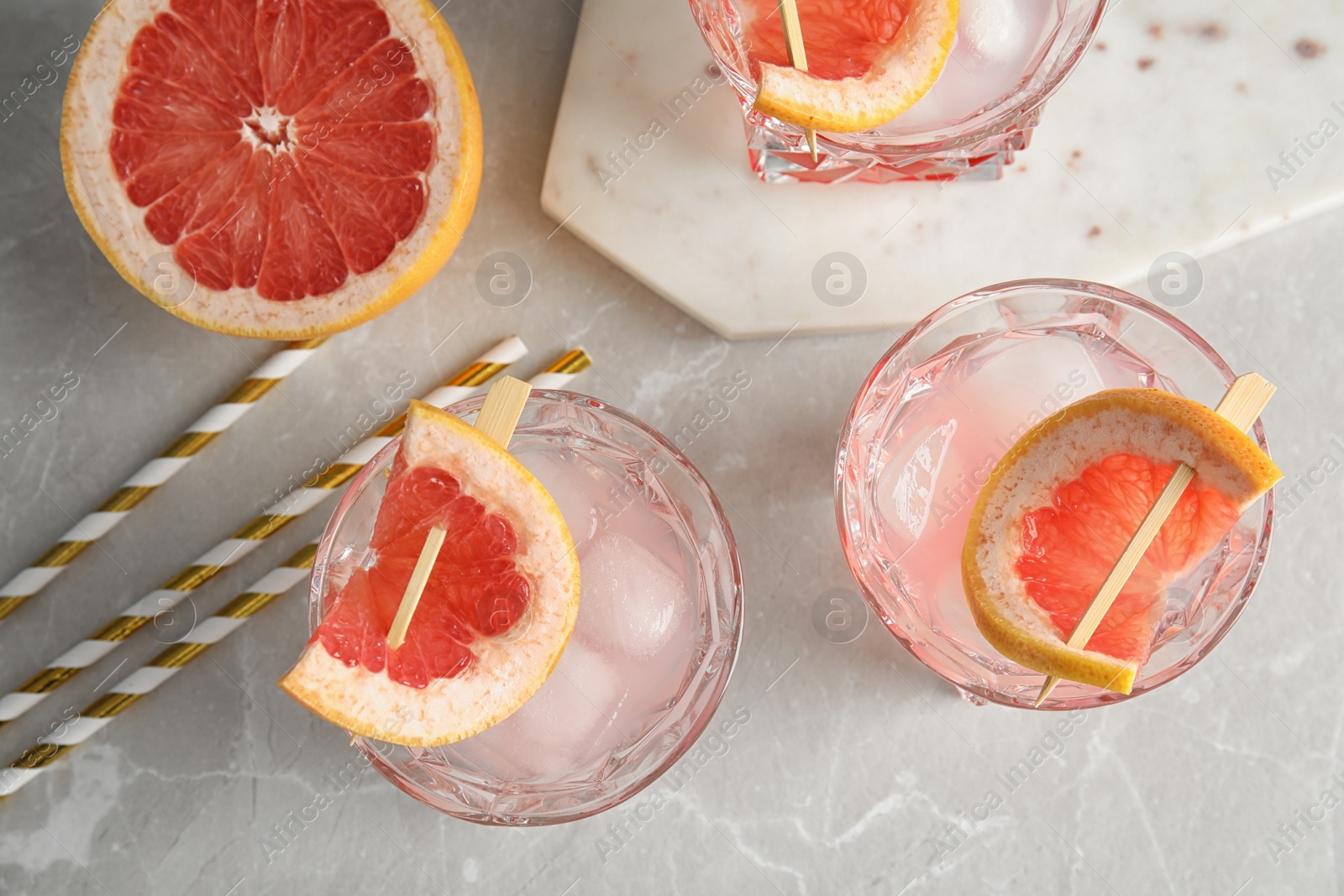 Photo of Flat lay composition with glasses of grapefruit cocktails on grey table