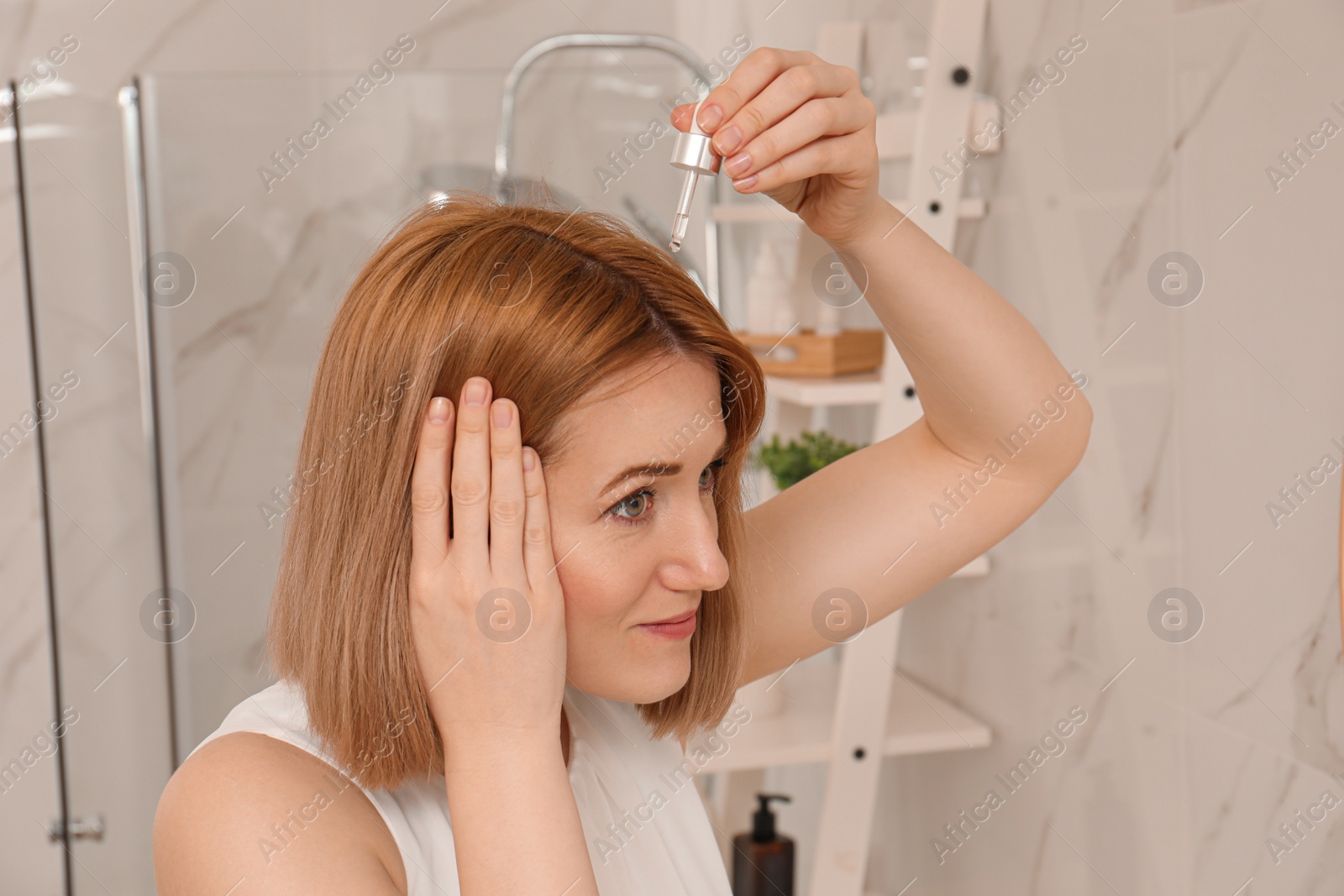 Photo of Woman applying oil onto hair at home. Baldness problem