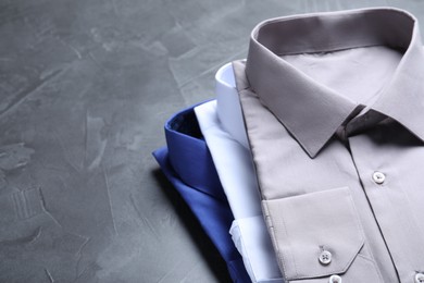 Photo of Stylish shirts on grey stone table, space for text. Dry-cleaning service