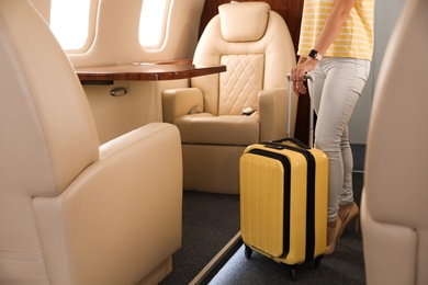 Photo of Woman with modern color suitcase on plane