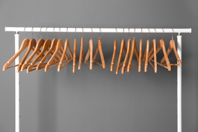 Photo of Clothes rail with wooden hangers on gray background