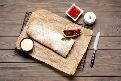 Photo of Delicious strudel with tasty filling served on wooden table, flat lay