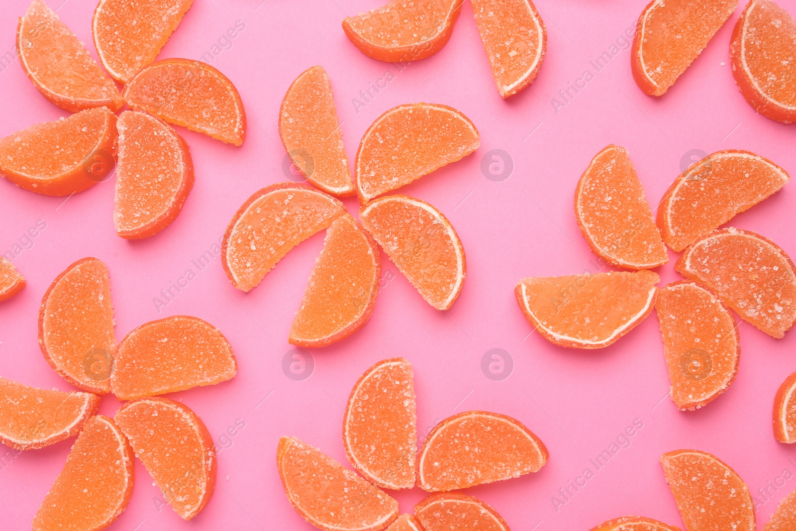 Photo of Delicious orange marmalade candies on pink background, flat lay