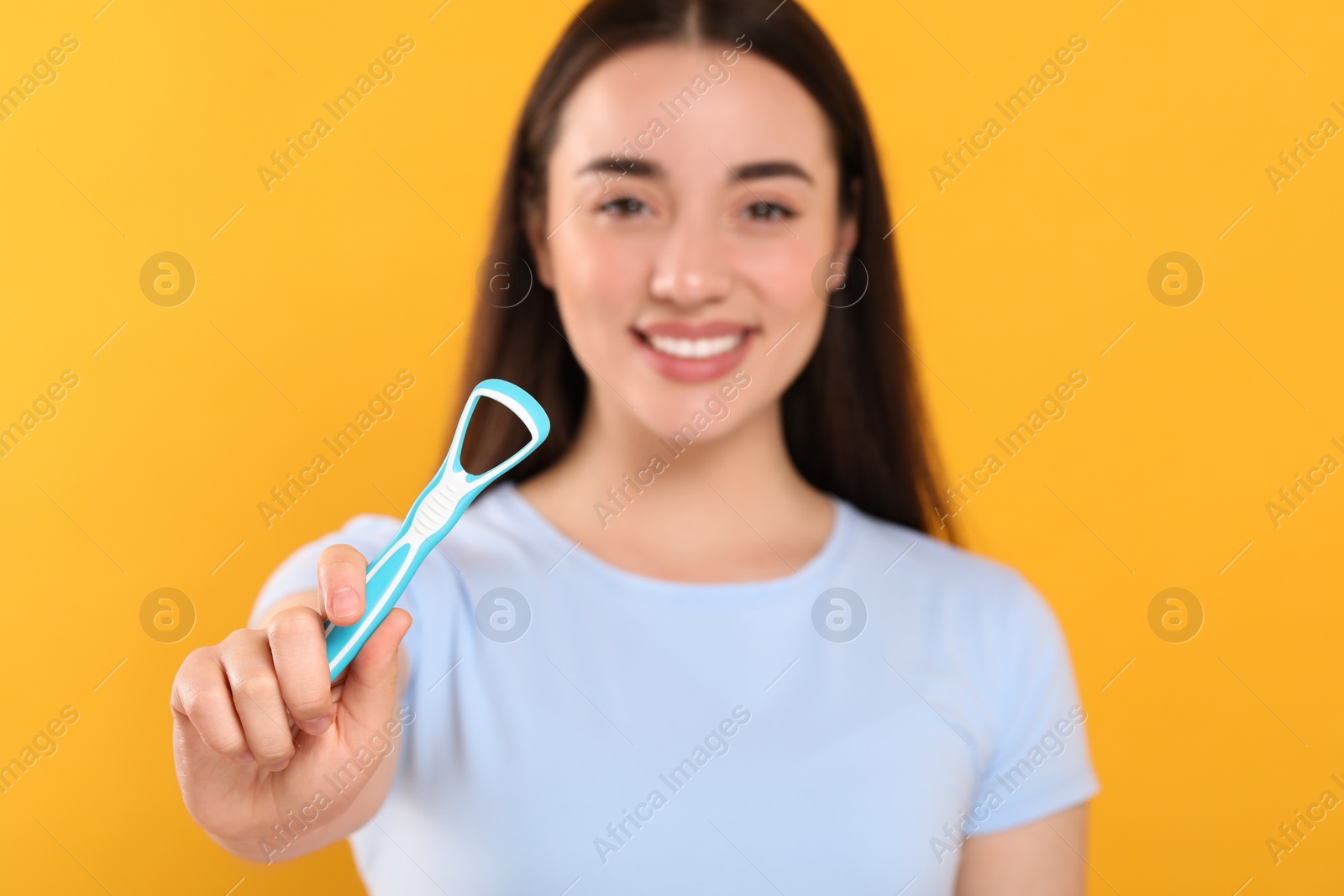 Photo of Happy woman with tongue cleaner on yellow background, selective focus