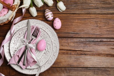 Photo of Festive table setting with painted eggs and tulips, flat lay with space for text. Easter celebration