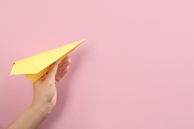 Photo of Woman holding paper plane on pink background, closeup. Space for text