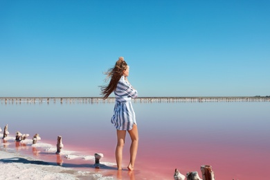 Beautiful woman posing near pink lake on summer day