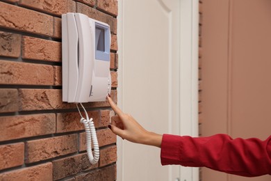 Photo of African-American woman pressing button on intercom panel indoors, closeup