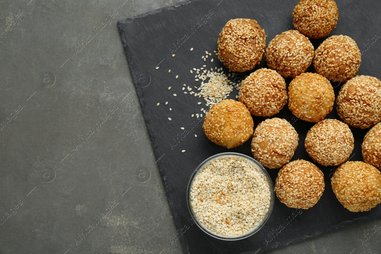 Photo of Delicious sesame balls and seeds on grey table, top view. Space for text